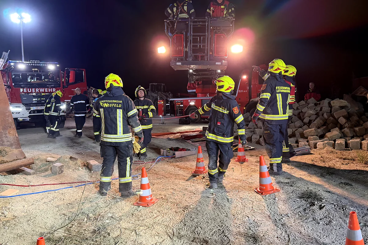 Feuerwehrleute im Einsatz in Neufeld bei Nacht mit Drehleiter und Einsatzfahrzeugen